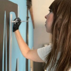 Portrait of Sarah Coleman painting a wall